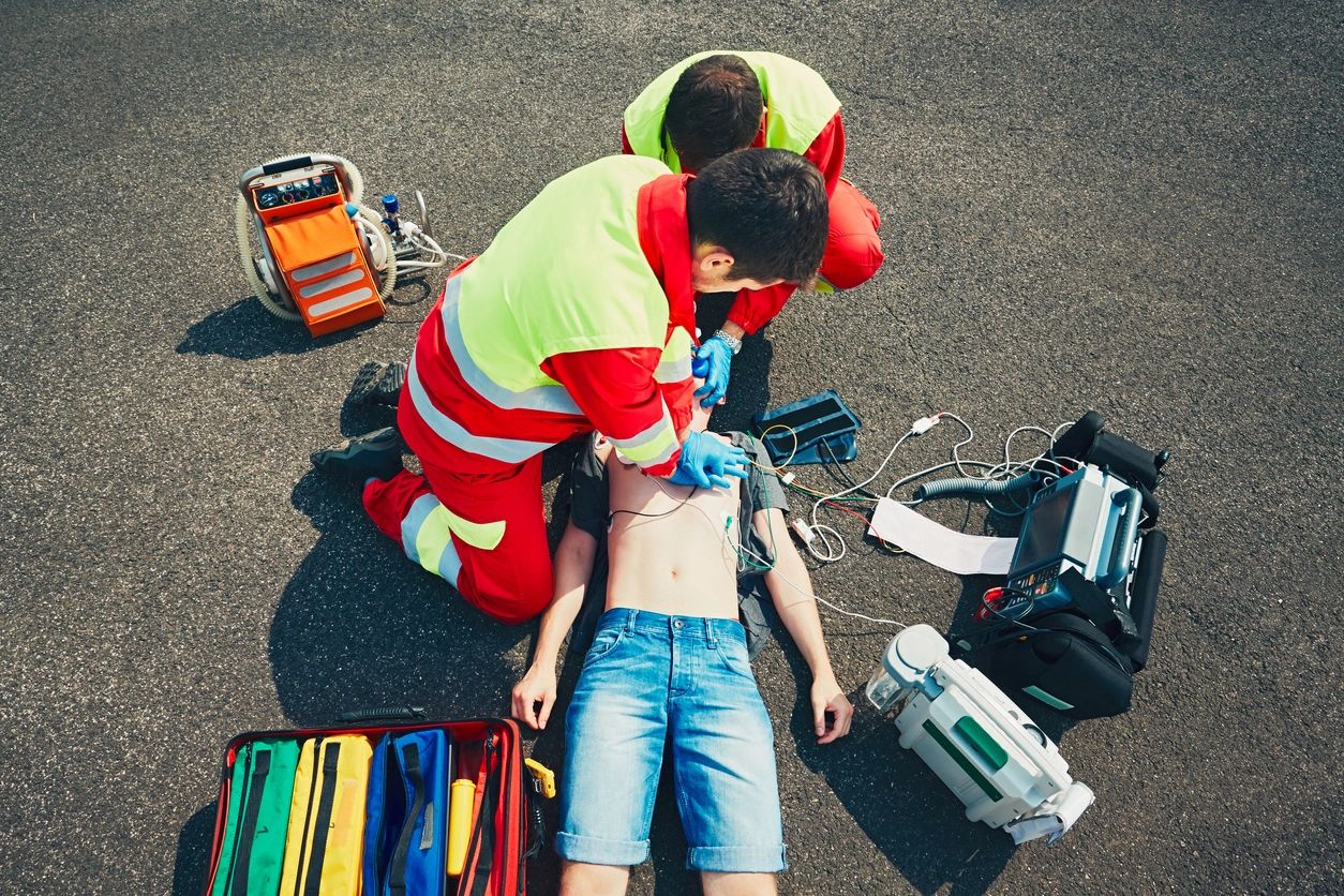 Two medical professional and a person lying on the ground
