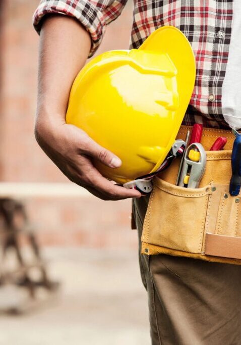 A man holding a yellow hard hat and some tools